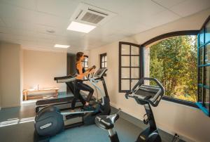 une femme qui roule sur un tapis de course dans une salle de sport dans l'établissement Hotel****Spa & Restaurant Cantemerle, à Vence