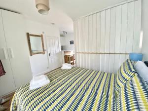 a bedroom with a bed with a yellow and blue striped blanket at Margate Seaside Retreat in Margate
