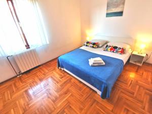 a bedroom with a bed with blue sheets and wooden floors at Apartments Luce in Rovinj