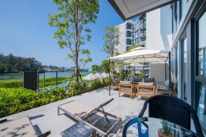 a patio with chairs and tables and an umbrella at Cassia Residences by Laguna Phuket in Bang Tao Beach