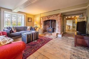 een woonkamer met een bank en een open haard bij Grove Farm House in Thornham Magna