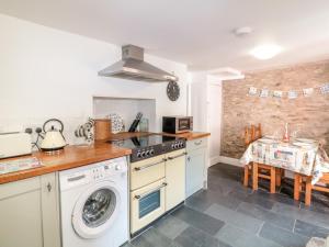 a kitchen with a washing machine and a table at Tops'l Cottage in Falmouth