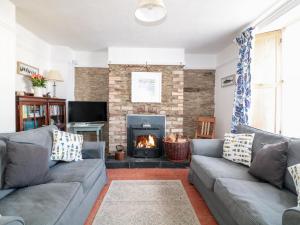 a living room with two couches and a fireplace at Tops'l Cottage in Falmouth