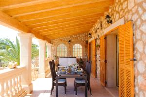 porche con techo de madera, mesa y sillas en Finca Cullera, en Calonge