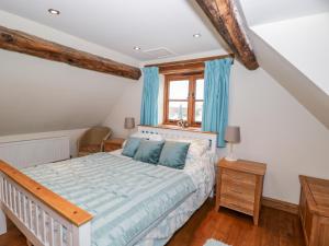 a bedroom with a bed with blue curtains and a window at Chapel Cottage in Stonehouse