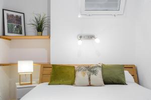 sypialnia z łóżkiem z białą pościelą i zielonymi poduszkami w obiekcie Lodging Apartments Illa Diagonal w Barcelonie