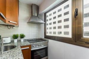 cocina con fogones, fregadero y ventana en Lodging Apartments Illa Diagonal, en Barcelona