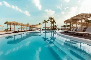 a pool at a resort with chairs and palm trees at Mitsis Norida in Kardamaina