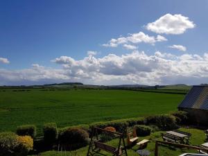 een uitzicht op een groot groen veld met een bank bij Rocking Chair Farmhouse in Alnwick