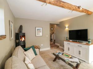 a living room with a couch and a tv at Woodside Barn in Thirsk