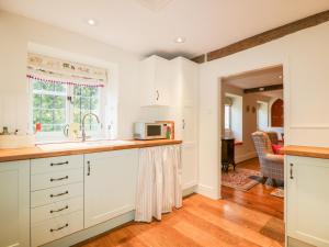 a kitchen with white cabinets and a microwave at Chapel Cottage in Stroud