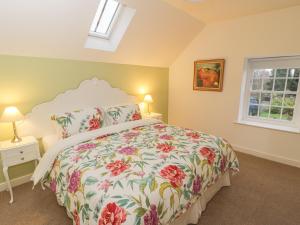 a bedroom with a bed with a floral bedspread at May Cottage in Scarborough