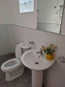 a bathroom with a white toilet and a sink at Two Season Tourist Inn in San Vicente