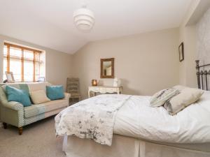a bedroom with a bed and a chair and a mirror at 1 Church Barns in Great Driffield
