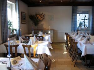 uma fila de mesas num restaurante com mesas e cadeiras brancas em Landgasthof Wellmann em Markt Taschendorf
