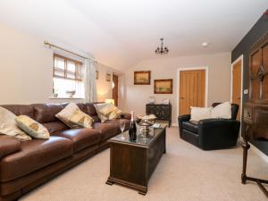 a living room with a brown couch and a table at 1 Church Barns in Great Driffield