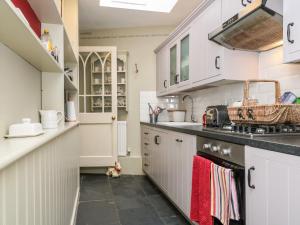 a kitchen with white cabinets and a stove top oven at October Cottage in Stroud