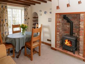 a living room with a fireplace and a table and a stove at Howe Green Cottage in York