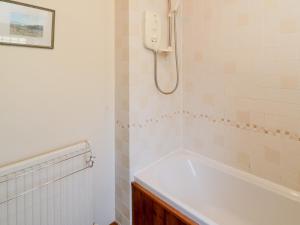 ein Badezimmer mit einer Badewanne und einem Telefon an der Wand in der Unterkunft Howe Green Cottage in York + 6 Fotos