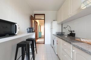 a kitchen with a counter with stools and a microwave at LovelyStay - Newly Decorated 2BR Flat with Free Parking in Vila Nova de Gaia