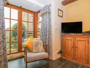 a living room with a tv and a chair and window at Weavers Cottage in Nailsworth