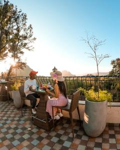 Ein Mann und eine Frau sitzen an einem Tisch auf einer Terrasse in der Unterkunft The Summer House, Pachmarhi - AM Hotel Kollection in Pachmarhi
