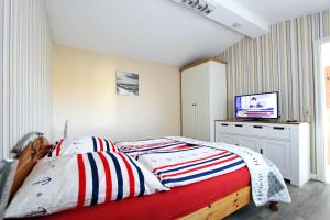 ein Schlafzimmer mit einem Bett und einem Fernseher an der Wand in der Unterkunft Käptn's Stuv in Hörnum