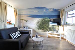 ein Wohnzimmer mit einem Sofa und einem Gemälde eines Strandes in der Unterkunft Käptn's Stuv in Hörnum
