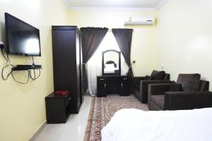 ein Schlafzimmer mit einem Bett, einem TV und einem Sofa in der Unterkunft Al Eairy Apartments - Hail 3 in Ha'il