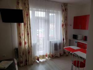 een keuken met een raam met gordijnen en een tafel bij Апартаменти Сонячне in Polyana