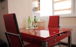 une table rouge avec trois bouteilles au-dessus dans l'établissement Apartments Deluxe, à Ivano-Frankivsk