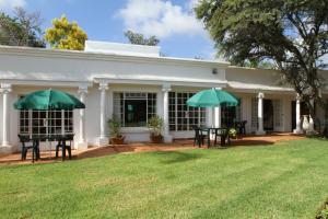 dos sombrillas verdes frente a una casa en Heatherdale Guesthouse & Shuttle Services, en Pretoria