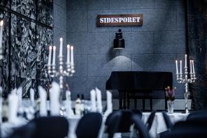 ein Esszimmer mit einem Tisch mit Kerzen und einem Klavier in der Unterkunft Hotel Sidesporet in Holbæk