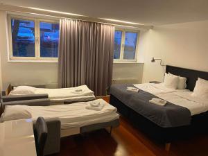a hotel room with two beds and two windows at Hotell Alfred Nobel in Karlskoga
