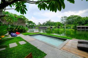 a swimming pool in the middle of a garden at The Westlake Hotel & Resort Yogyakarta in Yogyakarta