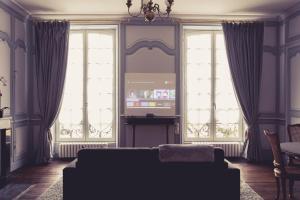 - un salon avec un canapé et 2 grandes fenêtres dans l'établissement La Maison de la Liberté Suite Jeanne Barret, à Poitiers
