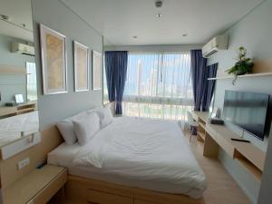 a bedroom with a white bed and a large window at Veranda Residence by VS in Na Jomtien