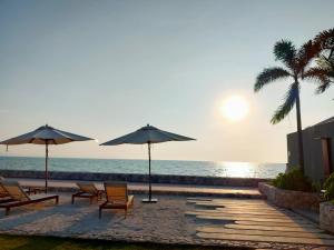 una playa con sillas y sombrillas y el océano en Veranda Residence by VS en Na Jomtien