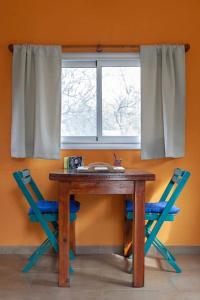 a table with two blue chairs and a window at Cabaña Anita in Merlo