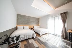1 dormitorio con 2 camas y ventana en 澎湖 就這兒旅居, en Magong
