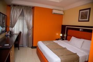 a bedroom with a bed with an orange wall at Sweet Spirit Hotel and Suites Danag - Port Harcourt in Port Harcourt