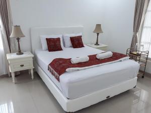 a white bedroom with a large white bed with red pillows at Surokarsan 9 House Yogyakarta in Yogyakarta