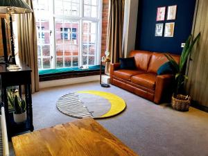 a living room with a leather couch and a rug at Cocoa Lily - River fronted studio with secure parking in York