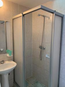 una ducha con una puerta de cristal junto a un lavabo en Cabañas Punto Verde, en La Serena