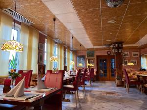 a restaurant with wooden tables and red chairs at Hotel da Rosario in Bad Neustadt an der Saale