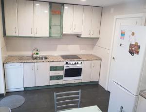cocina con armarios blancos, fregadero y nevera en Apartamento Ca'Sara, en Soria 17 fotos más