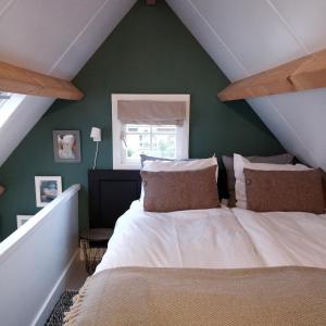 a bedroom with a white bed with a green wall at 't Hofhuys Oss in Oss