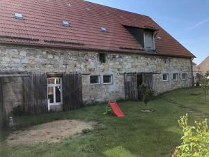 ein altes Steinhaus mit rotem Dach und Spielplatz in der Unterkunft Ferienwohnung Gans Auguste in Dohna