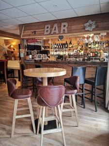 a bar with chairs and a table in a restaurant at Hôtel Restaurant Domaine de l'Adoux in Saint-Jean