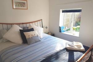 a bedroom with a bed with pillows and a window at The Garden Room in Chichester